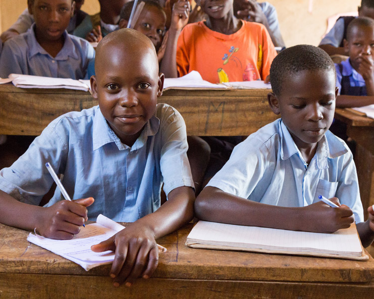 Grundschulversorgung Torodi Zwei nigerianische Grundschüler sitzen in der Schule, einer schaut in die Kamera